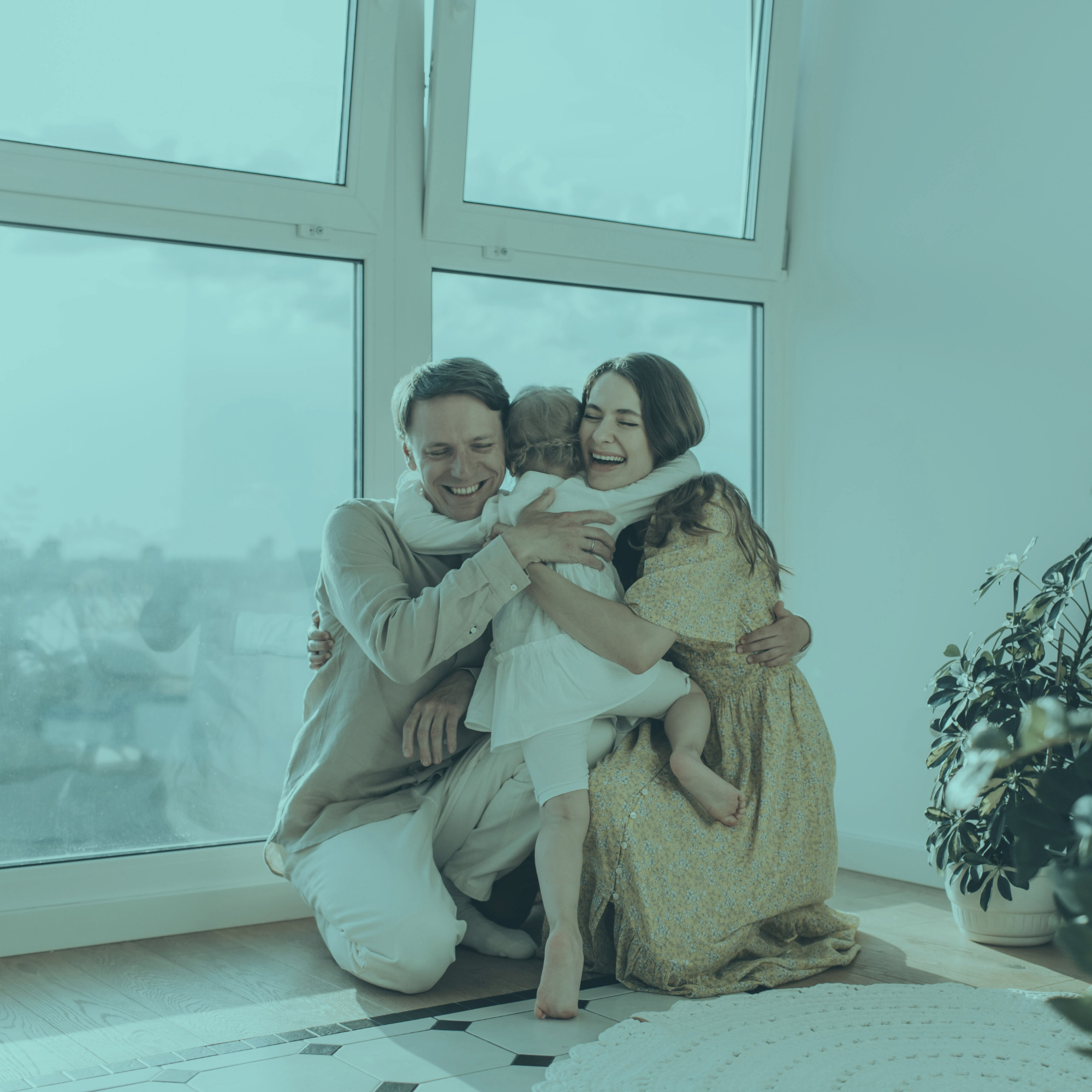 Uma família feliz se abraçando perto de uma janela grande.